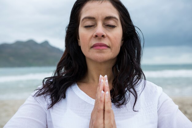 Donna che esegue yoga sulla spiaggia