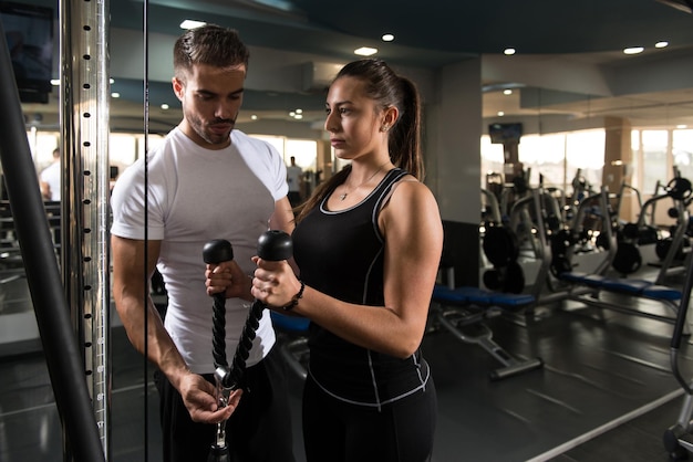 Donna che esercita i bicipiti con il suo personal trainer