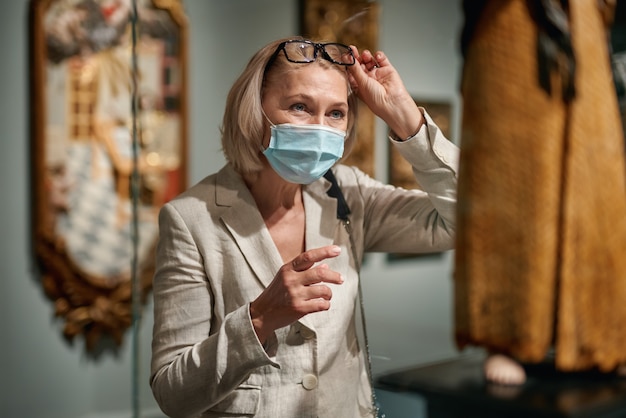 Donna che esplora le esposizioni medievali nel museo che indossa una maschera antivirus