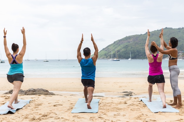 Donna che fa addestramento Yoga al suo studente sulla spiaggia tropicale in Tailandia