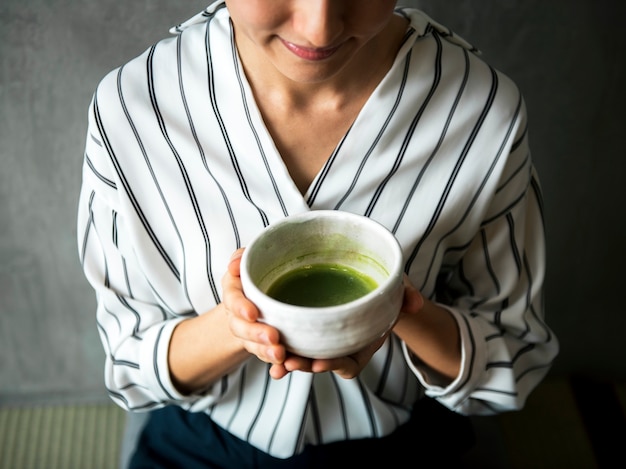 Donna che fa cerimonia giapponese del tè verde orientale