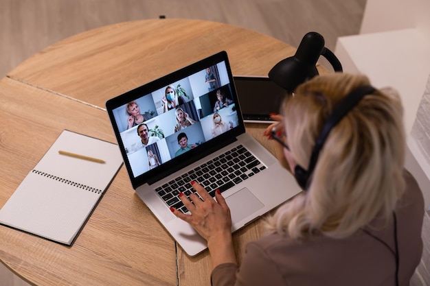 Donna che fa chat video con i colleghi al laptop in ufficio, primo piano