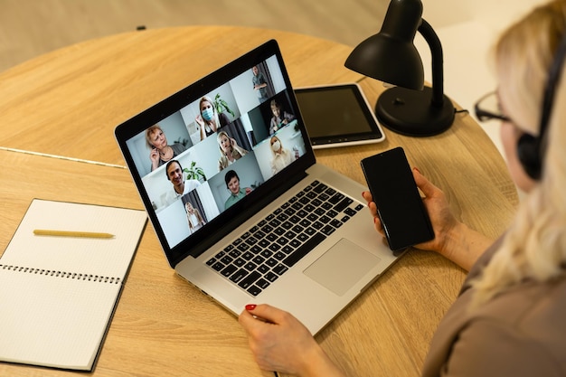 Donna che fa chat video con i colleghi al laptop in ufficio, primo piano