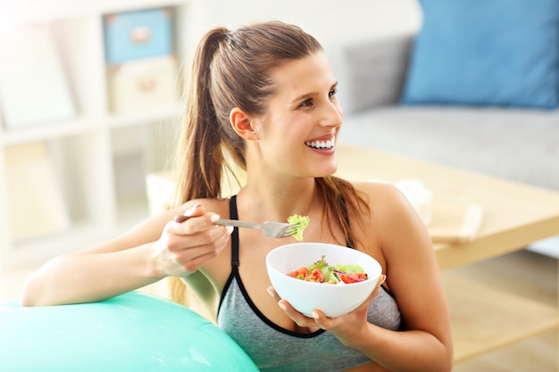 Donna che fa esercizi di fitness a casa in appoggio sulla palla