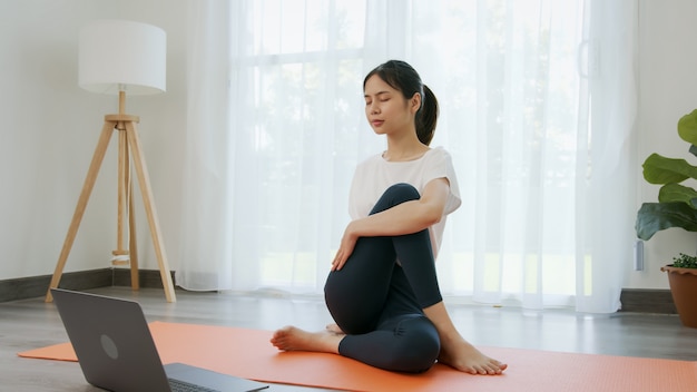 Donna che fa esercizi di yoga e guarda video tutorial online