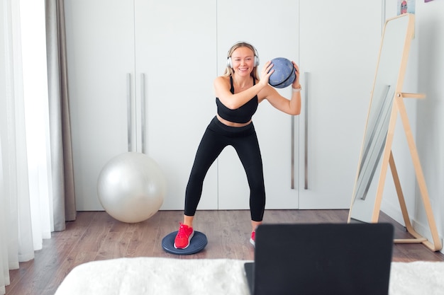 donna che fa esercizio di fitness a casa usando la palla