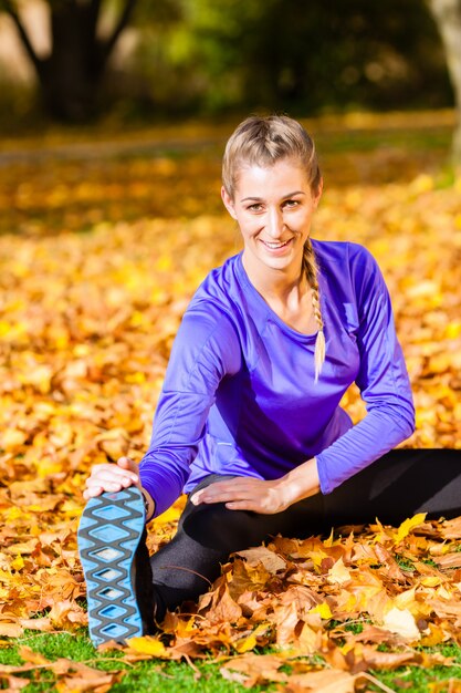 Donna che fa ginnastica nel fogliame di autunno