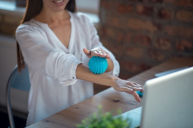 Donna che fa il massaggio delle braccia mentre era al lavoro