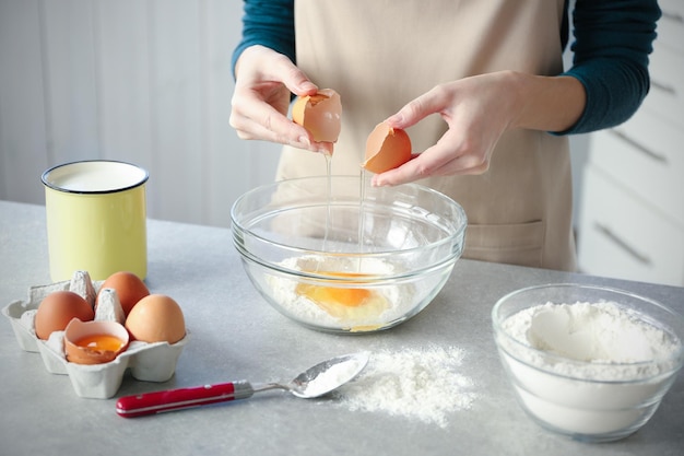 Donna che fa la pasta in una ciotola di vetro in cucina