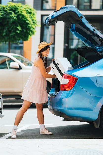 Donna che fa la valigia nel bagagliaio dell'auto