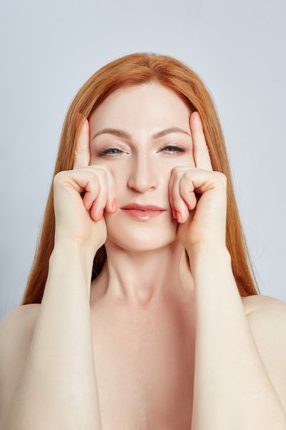 Donna che fa massaggio facciale, ginnastica, linee di massaggio e occhi e naso in plastica. Tecnica di massaggio contro rughe e ringiovanimento della pelle.