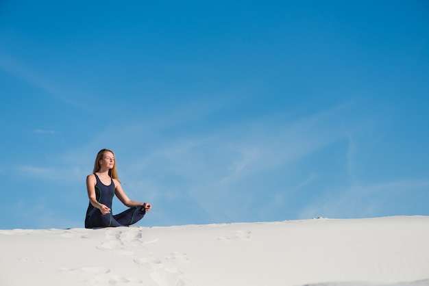 Donna che fa meditazione nella sabbia del deserto