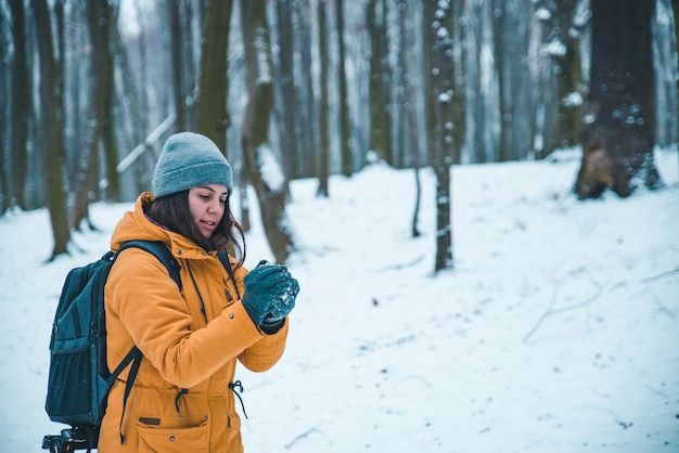 Donna che fa palla di neve nella foresta innevata. divertirsi