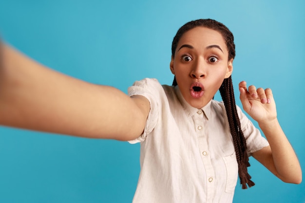 Donna che fa selfie guardando la fotocamera con occhi grandi e bocca aperta punto di vista foto