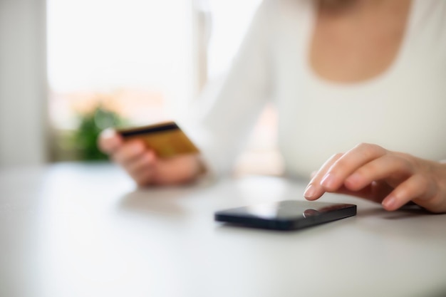 Donna che fa shopping online utilizzando carta di debito e cellulare Mani femminili che tengono la carta di credito su mobi