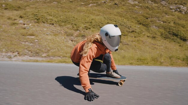 Donna che fa skateboard e fa acrobazie tra le curve su un passo di montagna