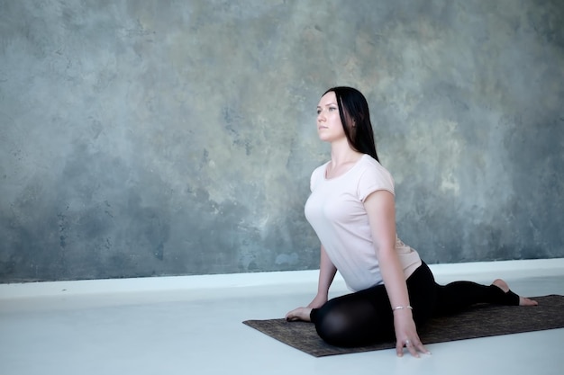 Donna che fa variazione della posa del piccione re con una gamba Eka Pada Radjakapotasana