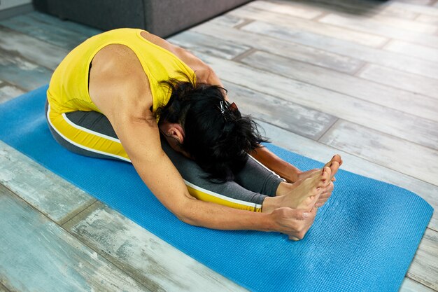 Donna che fa yoga a casa, facendo esercizi di stretching.