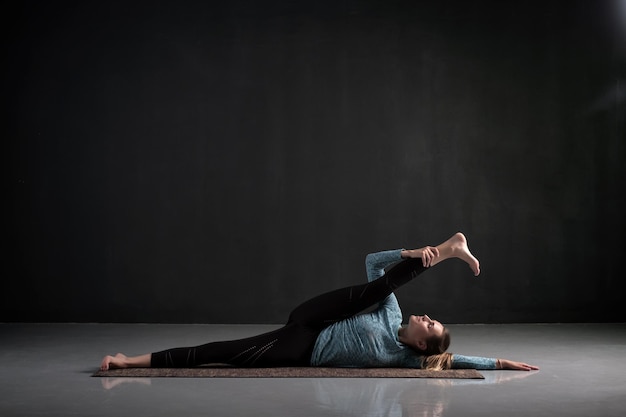 Donna che fa yoga asana Anantasana o sollevamento gambe reclinabili laterali