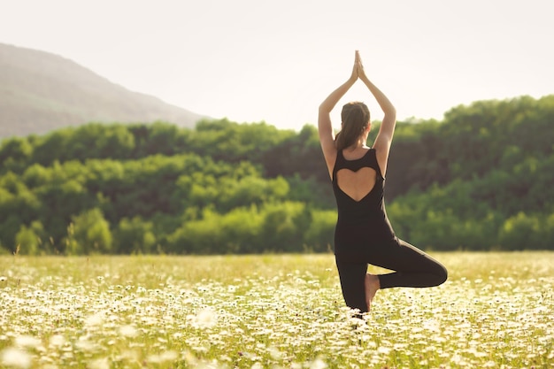 Donna che fa yoga da dietro sullo sfondo della natura