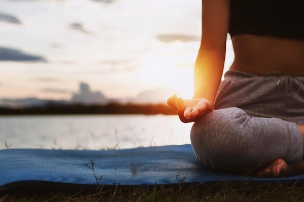 Donna che fa yoga in riva al lago la sera