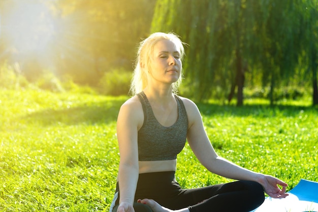 Donna che fa yoga in un parco cittadino in riva al fiume in estate