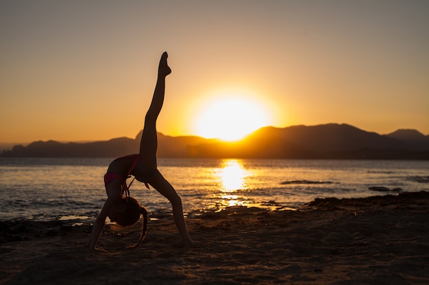 donna che fa yoga sulla natura all'aperto all'alba