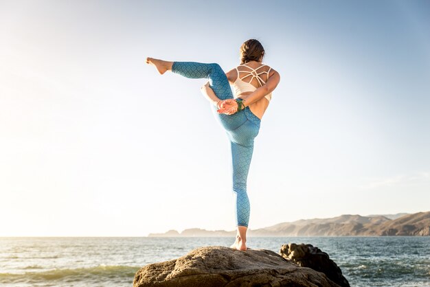 Donna che fa yoga sulla spiaggia