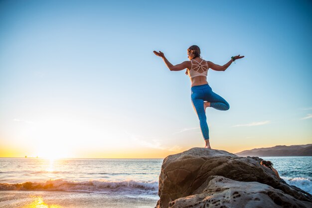 Donna che fa yoga sulla spiaggia