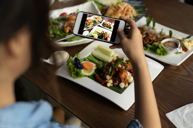 Donna che fotografa cibo tramite smartphone. Donna che scatta foto di un delizioso pranzo in un ristorante da caricare su un social media.