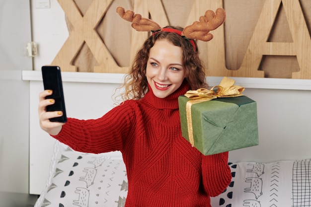 Donna che fotografa con il regalo di Natale