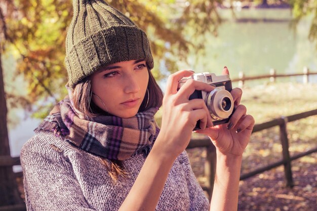 Donna che fotografia mentre è seduta in parco durante l'autunno