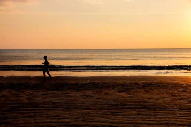 Donna che funziona sulla spiaggia al tramonto