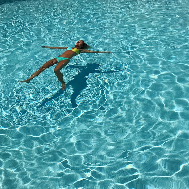 Donna che galleggia sull'acqua in piscina