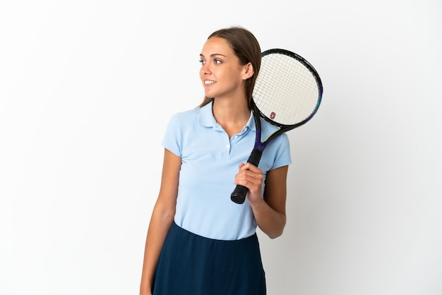 Donna che gioca a tennis sopra il muro bianco isolato che guarda di lato