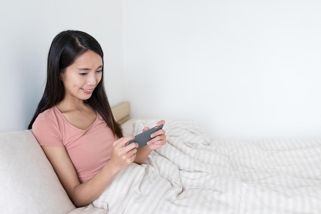 Donna che gioca a videogiochi sul cellulare nella camera da letto