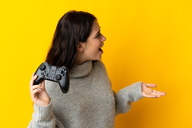 Donna che gioca con un controller per videogiochiisolrted su sfondo giallo con espressione facciale a sorpresa