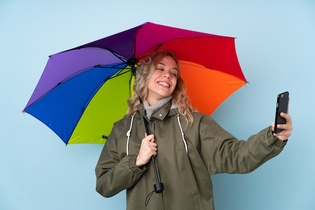 Donna che giudica un ombrello isolato sulla parete blu