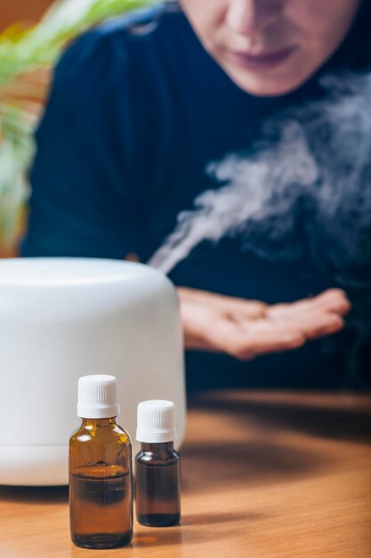 Donna che gode del profumo del vapore dell'aroma terapia dal diffusore di olio essenziale domestico o dall'umidificatore d'aria