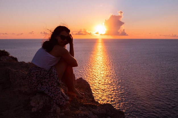 Donna che gode del tramonto sopra le vacanze estive del mare