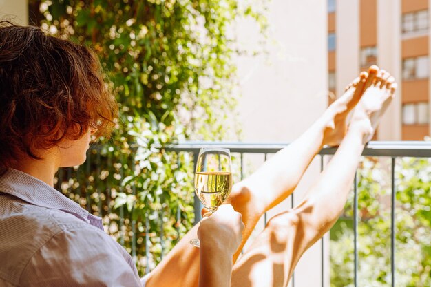 Donna che gode del vino bianco o dello champagne sul balcone