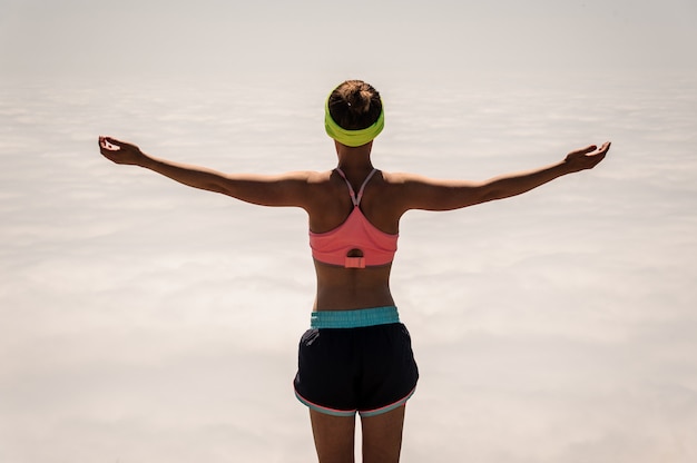 Donna che gode della natura nelle montagne e che osserva sul cielo con le mani sollevate.