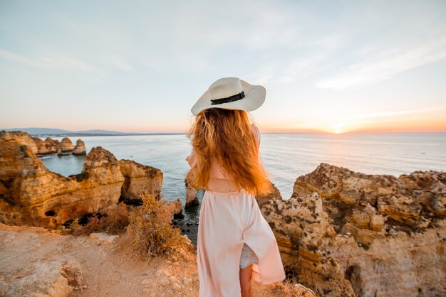 Donna che gode di una splendida vista sulla costa rocciosa durante l'alba a Lagos, nel sud del Portogallo