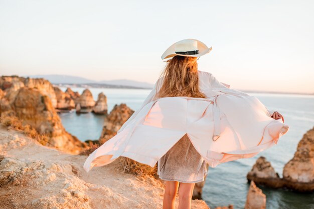 Donna che gode di una splendida vista sulla costa rocciosa durante l'alba a Lagos, nel sud del Portogallo