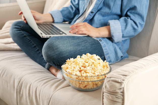 Donna che guarda film sul divano e mangia popcorn. Cibo per guardare film