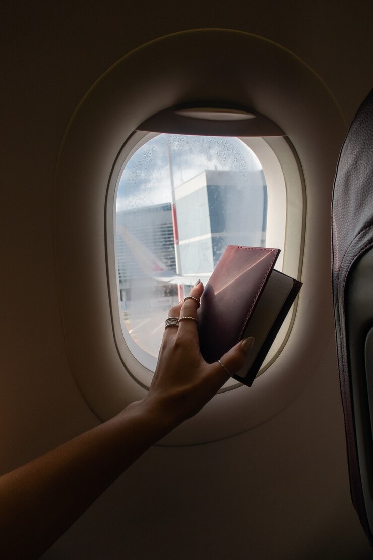 Foto donna che guarda fuori dal finestrino dell'aereo e mostra il passaporto