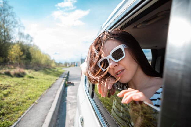 Donna che guarda fuori dal finestrino dell'auto viaggio su strada concetto di viaggio estate giornata di sole