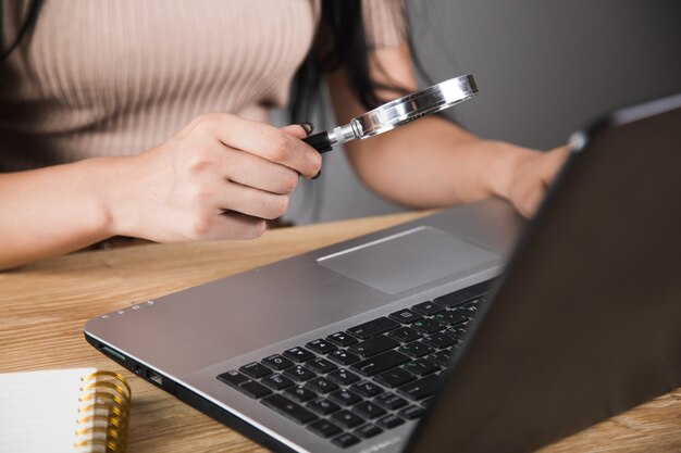 Donna che guarda il laptop con la lente d'ingrandimento