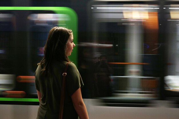 Donna che guarda il treno sfocato alla stazione della metropolitana