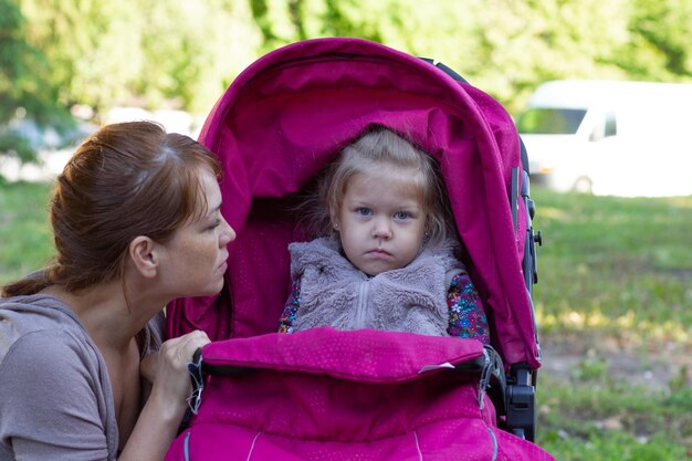 Donna che guarda la bambina offesa seduta nel passeggino